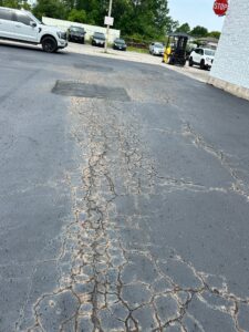 An asphalt parking lot with brown Discolored cracks