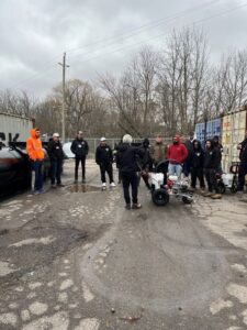 How to line paint training day at pavement depot, customers standing around a Titan 3500 line striping machine getting free training