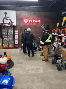 How to line paint training day at pavement depot, customers standing around a Titan 3500 line striping machine getting free training