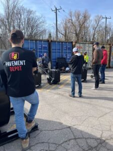 How to seal cracks in asphalt training day at pavement depot, customers standing around a RynoWorx crack filling machine getting free training