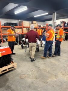 Customers in store at Pavement Depot Canada surrounding a Titan 3500 line striping machine getting free training on how to paint lines