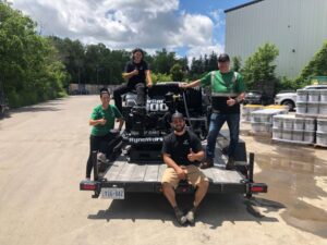 New customers Everline Coatings gathered around their new RynoWorx Airboss 300 Asphalt Sealing Machine at Pavement Depot