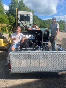 New customers gathered around their new RynoWorx Airboss 300 Asphalt Sealing Machine at Pavement Depot